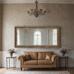 Versailles Majesty Mirror with ornate gold baroque frame above a classic brown sofa in elegant living room