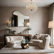 Aria cloud-shaped frameless mirror above a console in a living room with curved cream sofas and a crystal chandelier