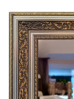 Close-up of the gold and antique silver baroque mirror frame corner with carved scrollwork