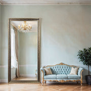 Luxurious living room with a large ornate mirror, light blue sofa, and chandelier.