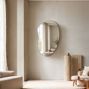 Orta bean-shaped frameless mirror hung vertically in a calm beige living room