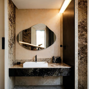Miroir sans cadre Piano en forme de galet au-dessus d’un meuble vasque en marbre