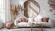 Rose gold round mirror with pampas grass and pink velvet pouf in bright living room with cream sofa and boho decor.