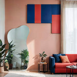 Serene curve irregular frameless mirror in colorful living room with coral wall, geometric art and navy sofa.