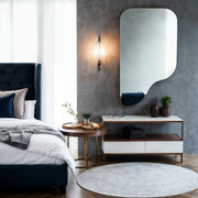 Specchio alto senza cornice Stilla con intaglio curvo sopra una consolle in camera da letto