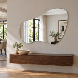 Specchio organico asimmetrico senza cornice Tria sopra una credenza sospesa in noce
