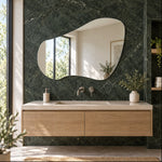 Specchio organico senza cornice Tria sopra un mobile lavabo in rovere in un bagno in marmo verde
